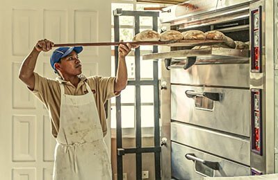 Baker pulling bread out of the oven