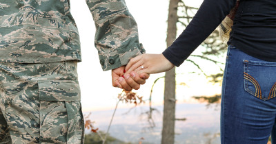 Military man and woman hold hand