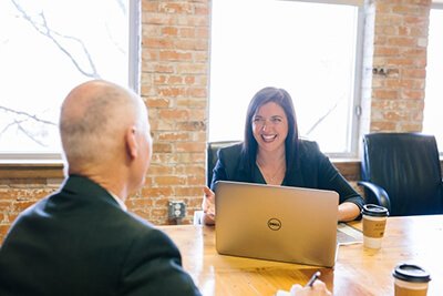 Smiling woman at her laptop in a meeting