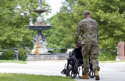 Military man pushing person in wheelchair