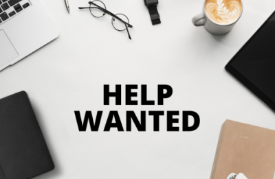help wanted spelled out on a surface with miscellaneous desk supplies