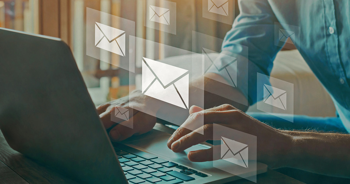 A person working on a laptop computer with several envelope symbols floating around them, indicating emails.