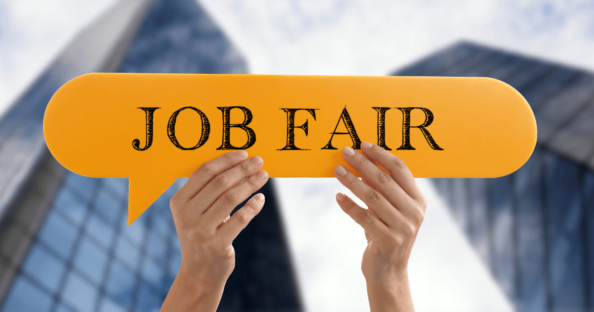 A pair of hands holding up a yellow sign with black text in front of some skyscrapers. The black text reads 'job fair.'