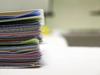 Stack of different colored files containing paper