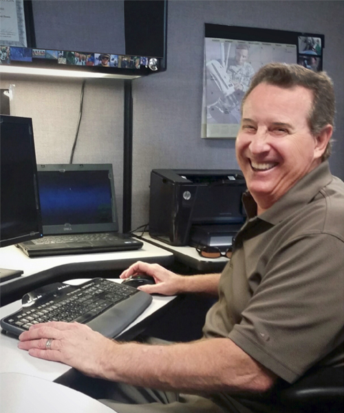 Image of Peter smiling at his desk