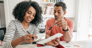 Two people sitting at a table, looking over receipts. 